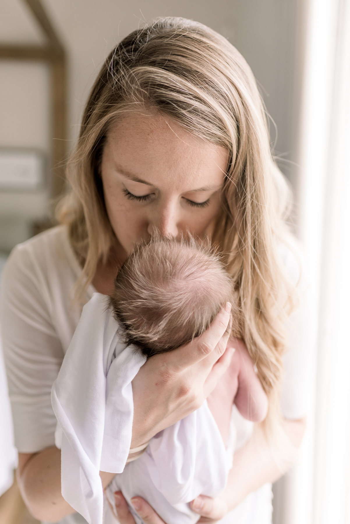 mom kissing baby's forehead in lifestyle newborn session 
